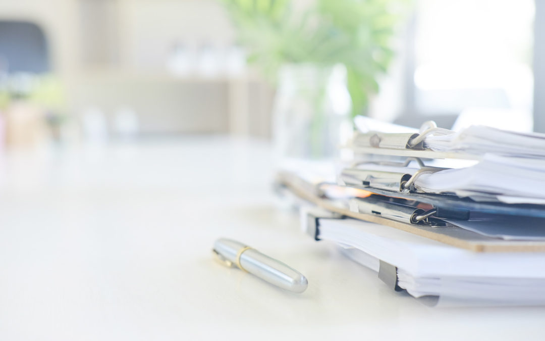 Stack of paper files and pen business equipment on office table.