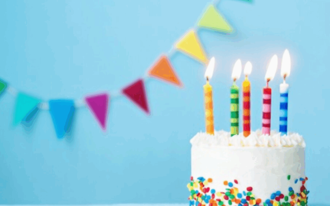 birthday cake and candles with colorful banners in background